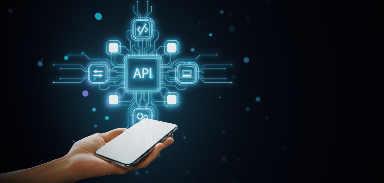 Person holding phone with holographic API icons connecting to symbols on dark blue background. Concept of online technology network. Person holding phone with holographic API icons connecting to symbols on dark blue background. Concept of online technology network.